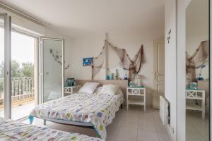 una camera da letto con due letti e un balcone di Vue Marine - Appartement proche plage a LʼÎle-Rousse