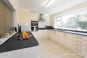 a kitchen with a counter with a bowl of fruit on it at Large bungalow with garden, sleeps 6, Wi-Fi & parking - Heathside Retreat in West Parley