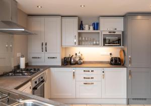 a kitchen with white cabinets and stainless steel appliances at The Stables in Braunton