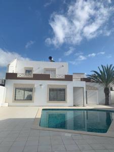 a white house with a swimming pool in front of it at Dar Midoun Villa with pool in center city in Midoun