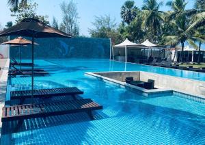 uma grande piscina com bancos e um guarda-sol em Trinco Waves em Trincomalee