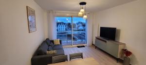 a living room with a couch and a flat screen tv at Une jolie vue - Appt 2 pièces Vue mer Balcon sud in Wimereux