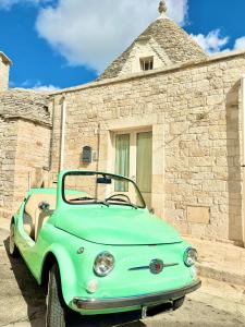 une voiture verte garée devant un bâtiment en pierre dans l'établissement Trulli Fenice Alberobello, à Alberobello