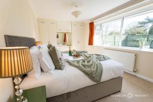1 dormitorio con 1 cama con sábanas y almohadas blancas en Large bungalow with garden, sleeps 6, Wi-Fi & parking - Heathside Retreat en West Parley