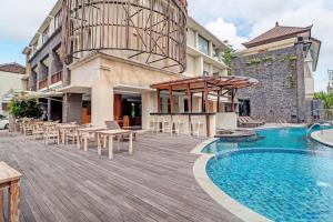 een zwembad met tafels en stoelen naast een gebouw bij Townhouse OAK Signature Bali in Sanur