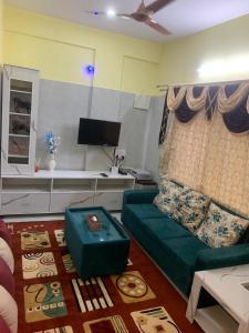 Cozy Prime-3BHK Near BIEC Exhibition Bangalore & IKEA في بانغالور: غرفة معيشة مع أريكة خضراء وطاولة