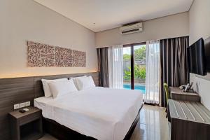 een hotelkamer met een bed en een raam bij Townhouse OAK Signature Bali in Sanur
