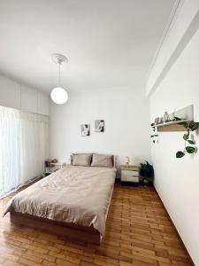 a white bedroom with a bed and a wooden floor at MaFi Apartment in Ioannina