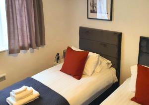a bedroom with two beds with red and white pillows at FW Haute Apartments at Wembley, Ground Floor 2 Bedroom and 1 Bathroom Flat, King or Twin beds and Double bed with FREE WIFI and FREE PARKING in London