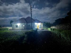 a white house with lights on in a field at Binga villa in Kisoro
