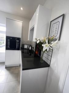 a white kitchen with a vase of flowers on a counter at 50 Wood St in Burton upon Trent