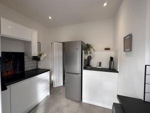 a kitchen with white cabinets and a stainless steel refrigerator at 50 Wood St in Burton upon Trent