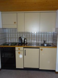 a kitchen with white cabinets and a sink and a stove at Ferienwohnung Inauen in Appenzell