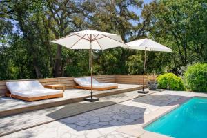 een patio met 2 parasols en een zwembad bij Villa Silia in the Gulf of Saint-Tropez in a natural setting in La Garde-Freinet