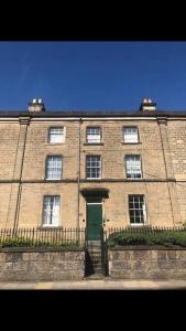 a large brick building with a green door at Lovely Bakewell apartment in Bakewell