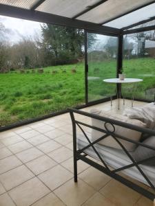 eine Terrasse mit einem Tisch und Blick auf ein Feld in der Unterkunft Maison au calme Plessala Le Mené in Saint-Udy
