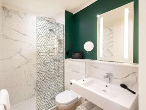 La salle de bains est pourvue d'un lavabo, de toilettes et d'un miroir. dans l'établissement Mercure Lyon Centre Brotteaux, à Lyon