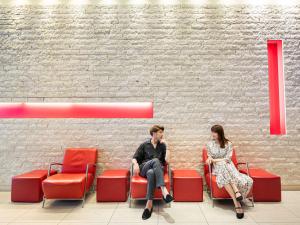 un hombre y una mujer sentados en sillas rojas en Mercure Hotel Sapporo, en Sapporo