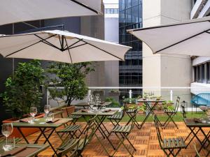 a patio with tables and chairs with umbrellas at Mercure Milano Agrate Brianza in Agrate Brianza