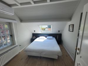 1 dormitorio con cama blanca y ventana en Parkhoeve Vakantiewoning, en Ham