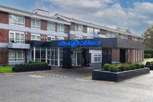 un hôtel avec un panneau à l'avant d'un bâtiment dans l'établissement Hilton Cobham, à Cobham