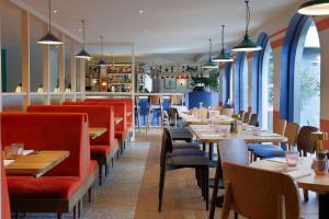 um restaurante com mesas de madeira e cadeiras vermelhas em Hilton Cobham em Cobham