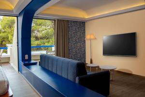 a hotel room with a couch and a flat screen tv at Ramada Loutraki Poseidon Resort in Loutraki