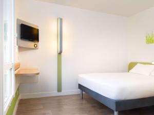 a bedroom with a bed and a tv on the wall at ibis budget Issy Les Moulineaux Paris Ouest in Issy-les-Moulineaux