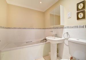 ein Badezimmer mit einem Waschbecken, einer Badewanne und einem WC in der Unterkunft Bowleaze Beach Apartment in Weymouth