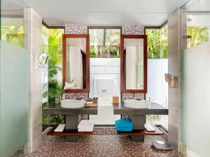 a bathroom with two sinks and two mirrors at Novotel Phu Quoc Resort in Phú Quốc