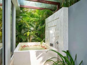 una vasca da bagno in una stanza con alberi di Novotel Phu Quoc Resort a Phu Quoc