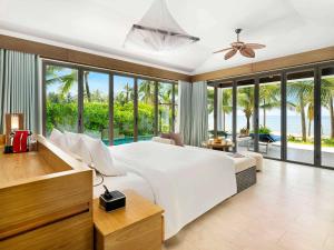 a bedroom with a large white bed with a view of the ocean at Novotel Phu Quoc Resort in Phu Quoc