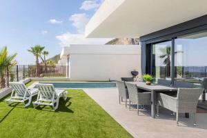 a patio with a table and chairs and a swimming pool at Casa con piscina climatizada y vistas al mar in Polop
