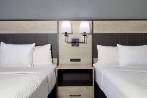 a hotel room with two beds with white sheets and lights at La Quinta Inn by Wyndham Stockton in Stockton