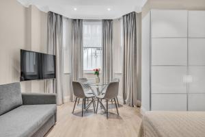 a living room with a couch and a table with chairs at Cleveland Residences Chelsea in London
