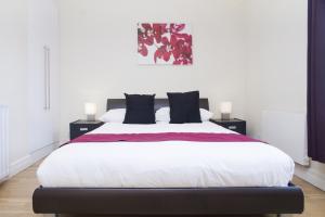 a bedroom with a large white bed with black pillows at Holiday Lets London K in London