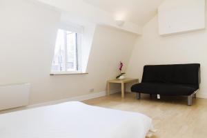 1 dormitorio con 1 cama y 1 silla negra en Holiday Lets London K, en Londres