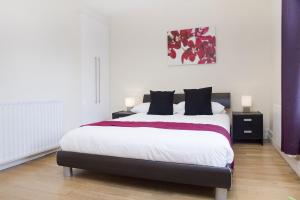 a bedroom with a large white bed with black pillows at Holiday Lets London K in London