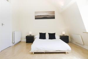 a white bedroom with a bed and two night stands at Holiday Lets London K in London