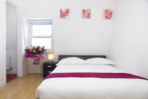 a white bedroom with a bed and a vase of flowers at Holiday Lets London - K in London +19 photos