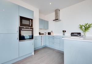 a white kitchen with white cabinets and appliances at 5 At The Beach in Weymouth
