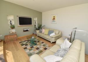 a living room with two couches and a flat screen tv at Tuppence View in Swanage