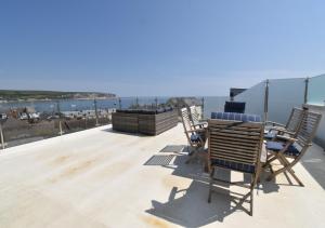 a deck with chairs and a table and a view of the ocean at Tuppence View in Swanage