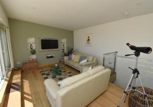 a living room with a couch and a television and a camera at Tuppence View in Swanage