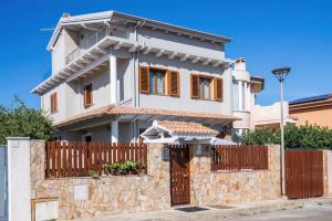 a white house with a wooden gate and a fence at B&B Le Ginestre in Portoscuso