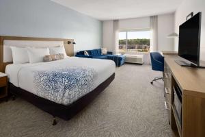 a hotel room with a bed and a flat screen tv at La Quinta Inn & Suites by Wyndham Locust Grove in Locust Grove