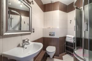 een badkamer met een wastafel, een toilet en een spiegel bij Your Holidays Gryfa Pomorskiego in Międzyzdroje