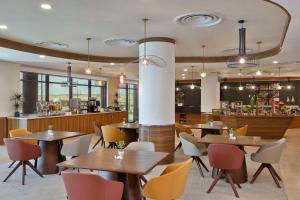 Khuraybah的住宿－Hampton By Hilton Sharma - NC1，一间带桌椅的餐厅和一间酒吧