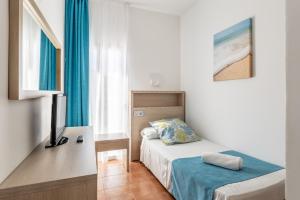 1 dormitorio con 1 cama y escritorio con TV en Hostal Neptuno, en Paguera
