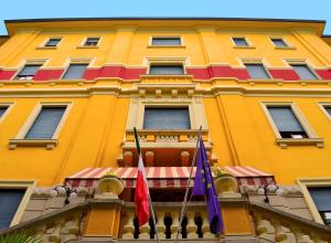 a yellow building with two flags in front of it at Hotel Valentini in Salsomaggiore Terme